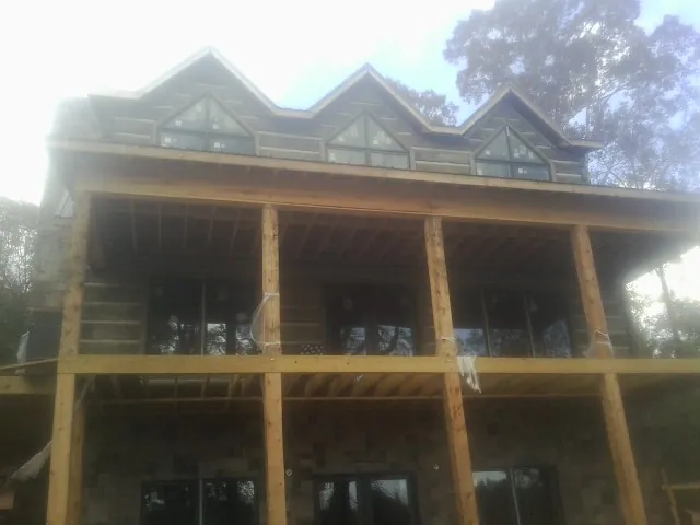Dormers and porch framing on a large log home under construction — Roof Coating work by our crew in Amory