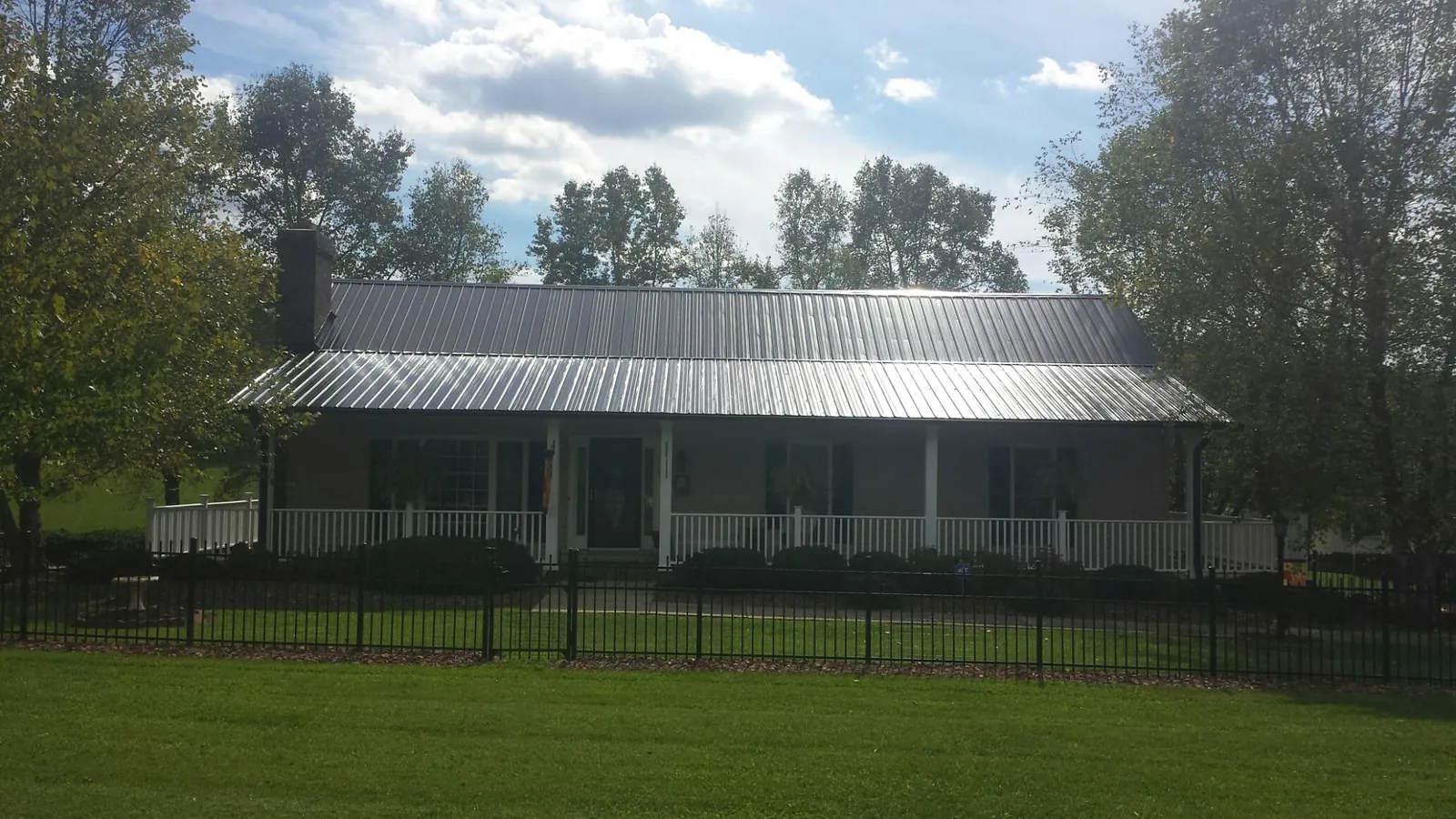 Gray metal roof on a brick ranch with a full width front porch — Gutter Guard Installation work by our crew in Amory